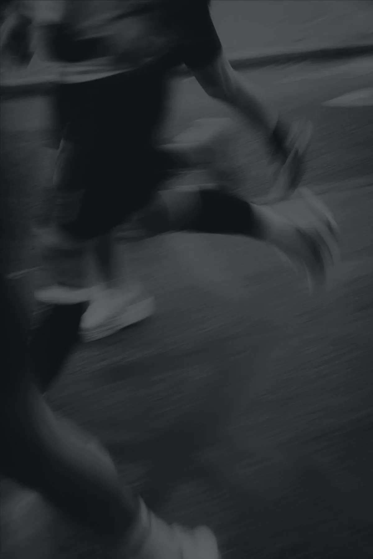 Runners mid-stride at speed, motion-blurred in low light